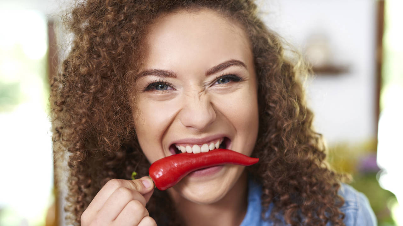 Mujer comiendo una guindilla tipo chile