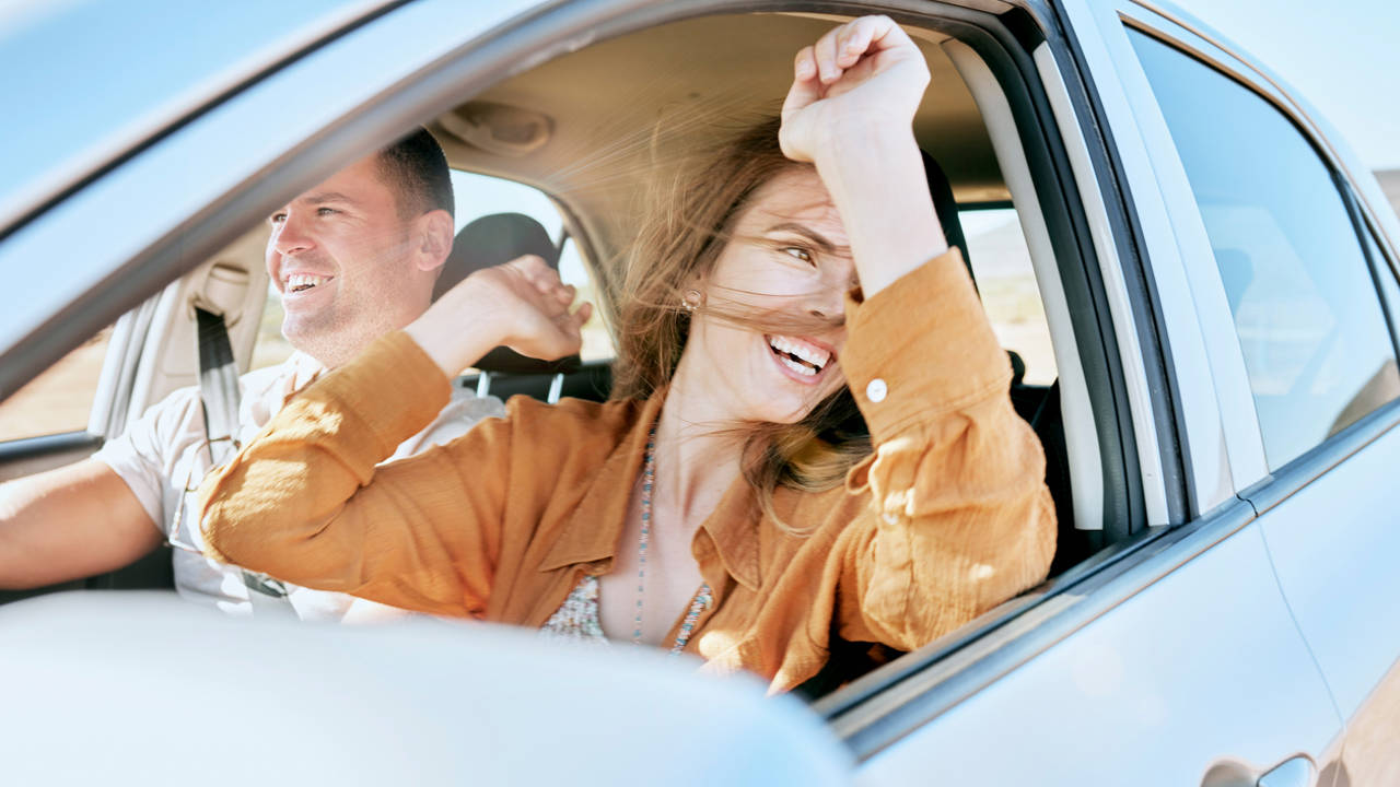 Pareja viajando con las ventanillas del coche bajadas