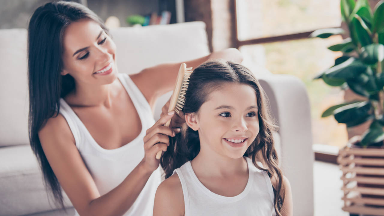 Mujer peinando el cabello largo de una niña