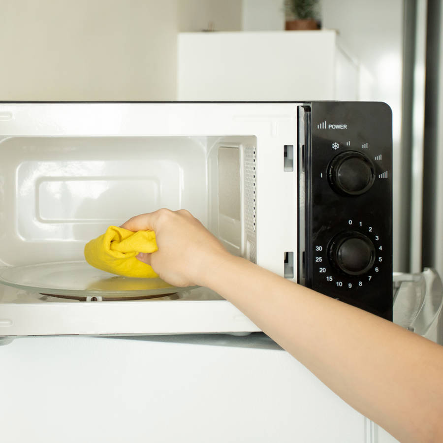 Mujer limpiando un microondas por dentro