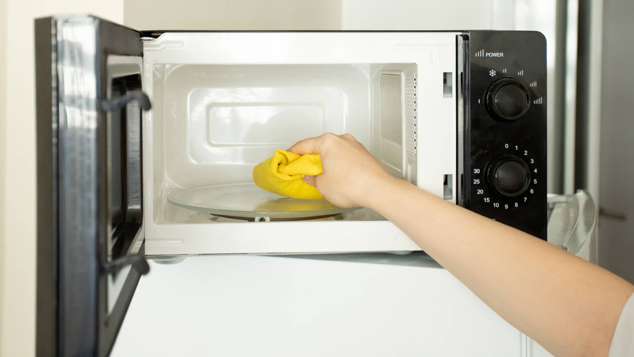 Mujer limpiando un microondas por dentro