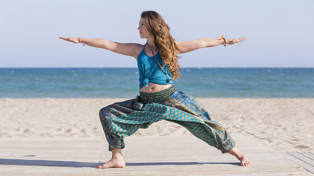 Mujer practicando yoga en la playa