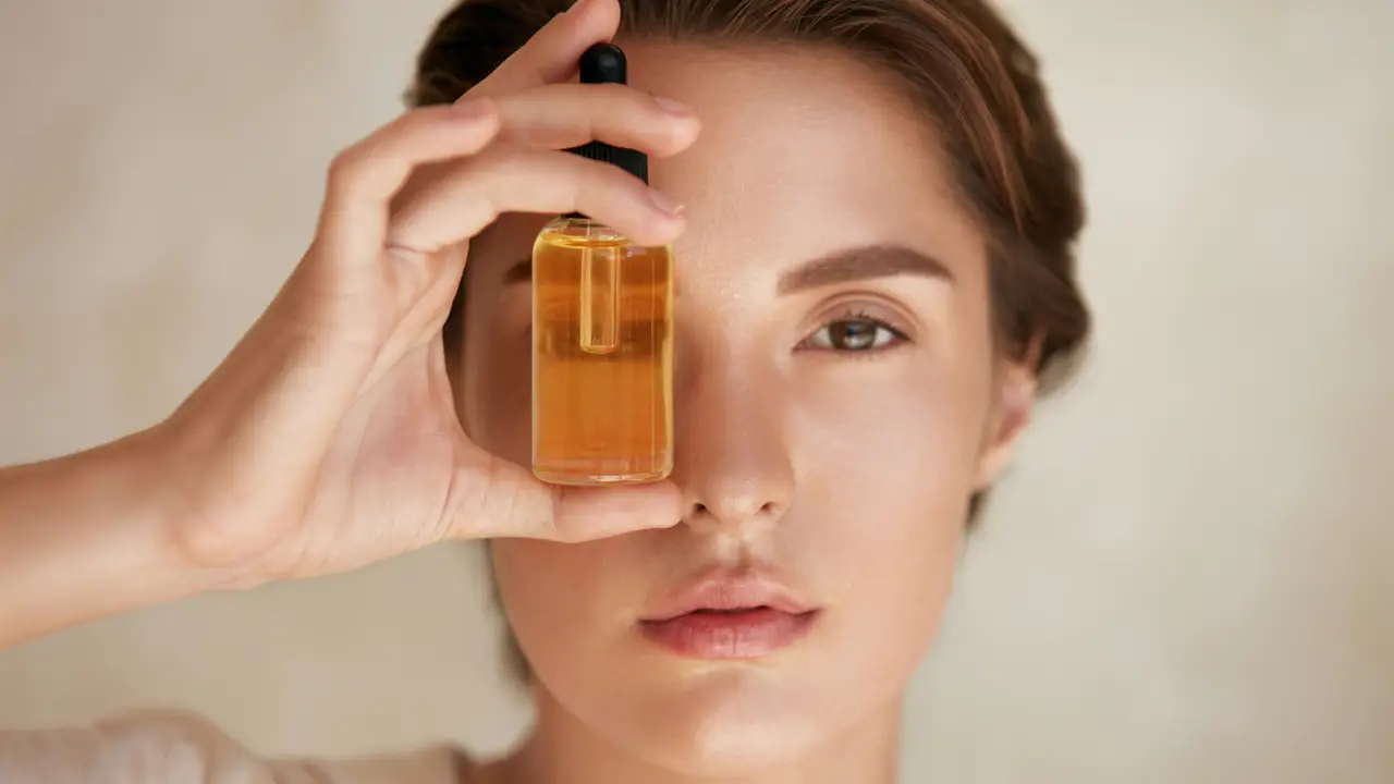 Mujer con un frasquito de aceite entre los dedos 