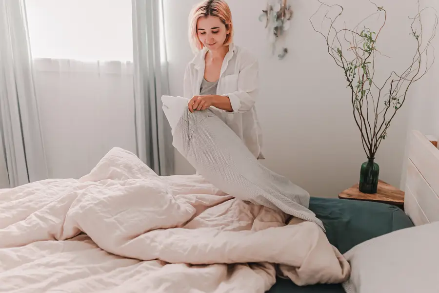 Mujer poniendo ropa de cama limpia