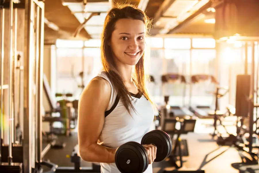 Chica haciendo pesas en el gimnasio