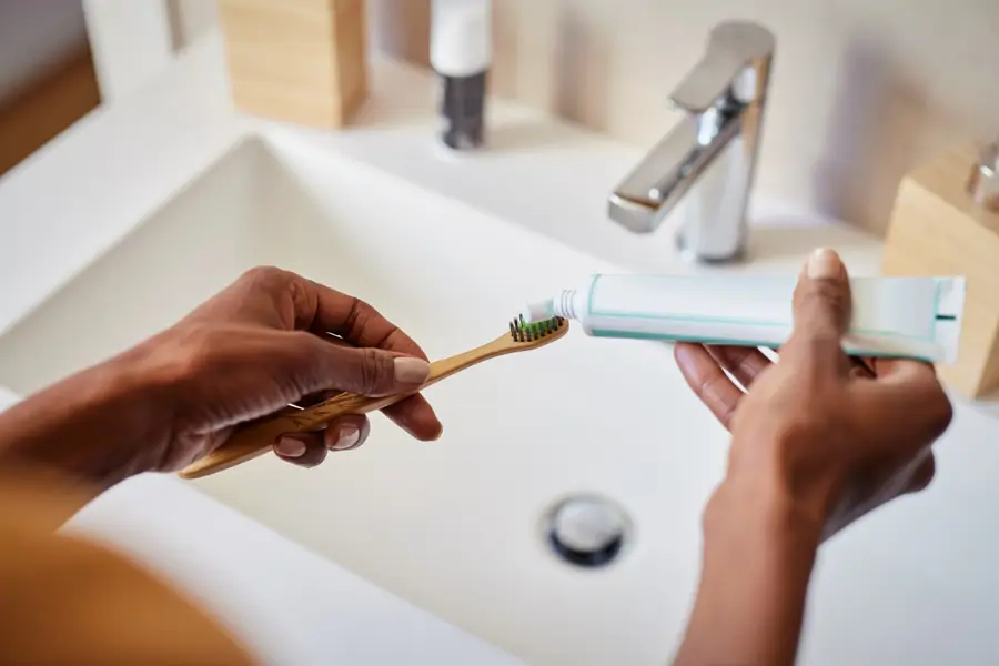 Mujer poniendo dentífrico en el lavabo