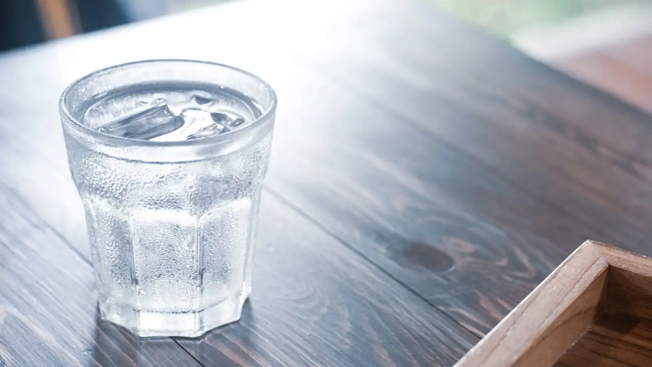 Vaso con hielo sobre mesa de madera maciza