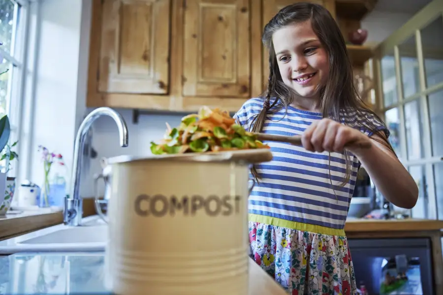 Niña colocando restos de verduras en el cubo del compost