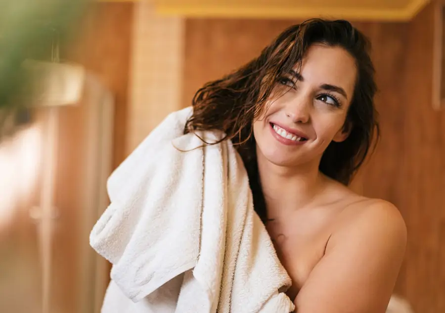 Mujer secándose el pelo con toalla después de lavárselo